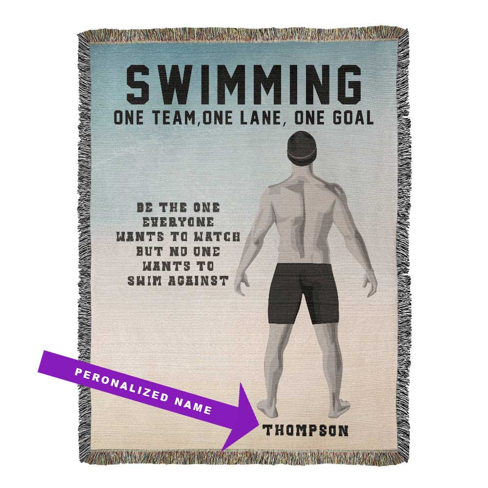 A personalized woven blanket with a swimmer's back view on it, featuring the text 'SWIMMING ONE TEAM, ONE LANE, ONE GOAL' along with a motivational quote and the name 'THOMSON'. The blanket has decorative fringe on the sides. Name is customizable