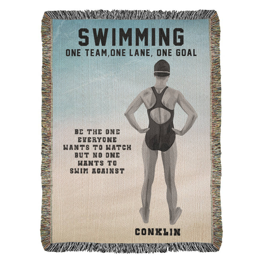A woven blanket with a swimmer on it, featuring the text 'SWIMMING ONE TEAM, ONE LANE, ONE GOAL' and the name 'CONKLIN'.