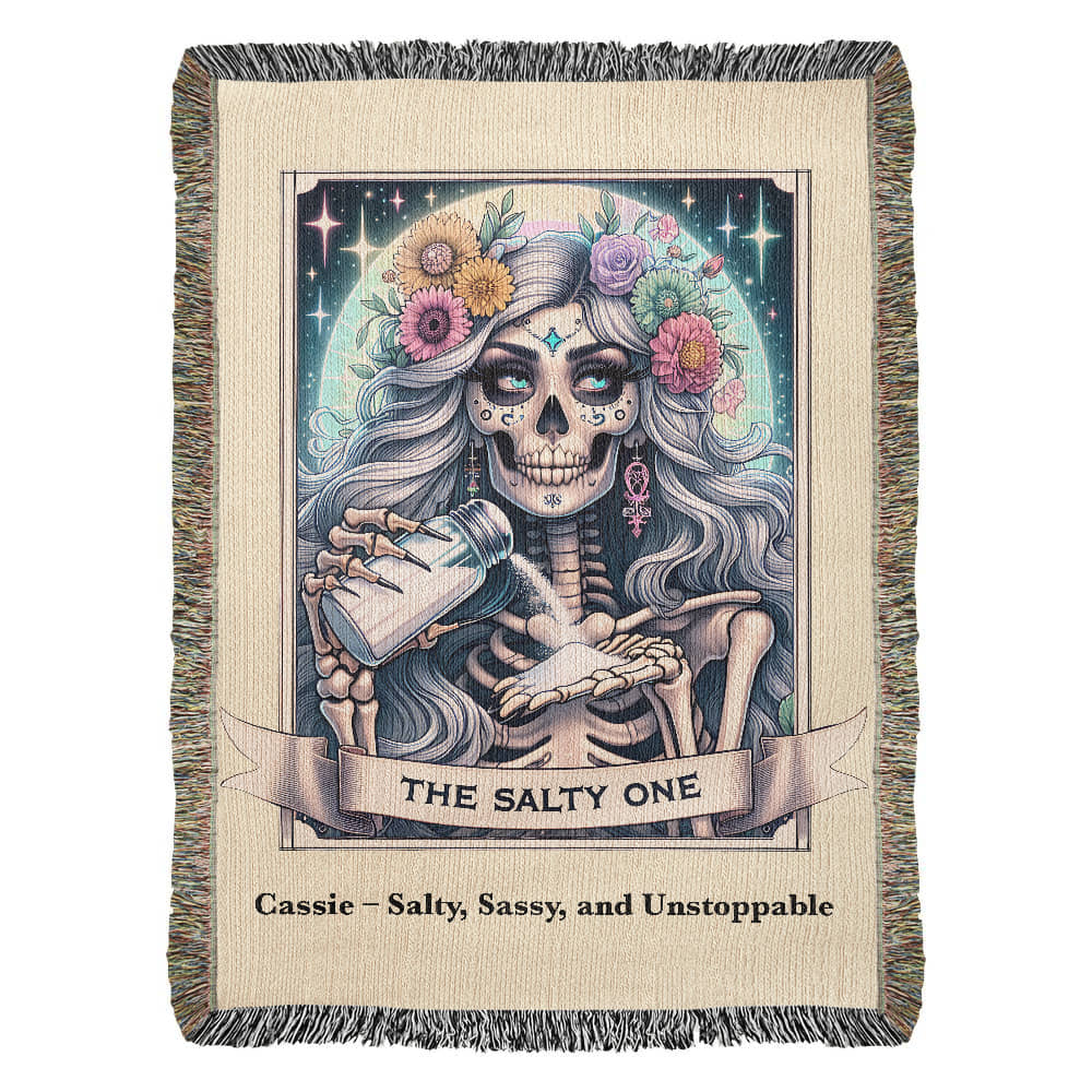 Woven blanket with a tarot card design featuring a skeleton with silver hair and a floral crown, with the text 'THE SALTY ONE' and a personalized name and phrase.