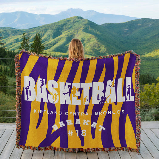 Person holding a basketball-themed blanket with mountains in the background