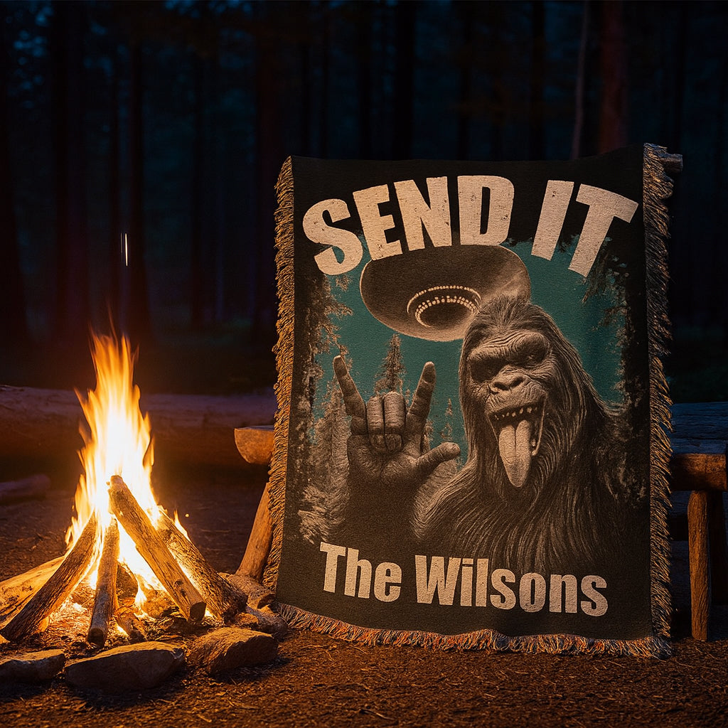 Blanket with a Sasquatch a UFO and text 'SEND IT and personalized name The Wilsons' in front of a campfire at night.