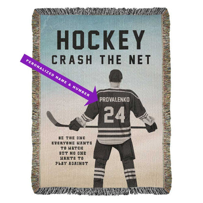 A personalized woven blanket with a hockey player in motion, the text 'HOCKEY CRASH THE NET' and customizable player name and jersey number, along with a motivational quote saying Be the one everyone wants to watch but no one wants to play against. 
