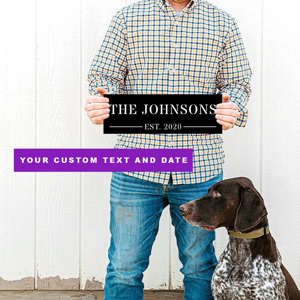 Man holding a personalized metal wall art sign with 'The Johnsons' and a dog sitting next to him. The name and date are customizable by FunLifeNow.com