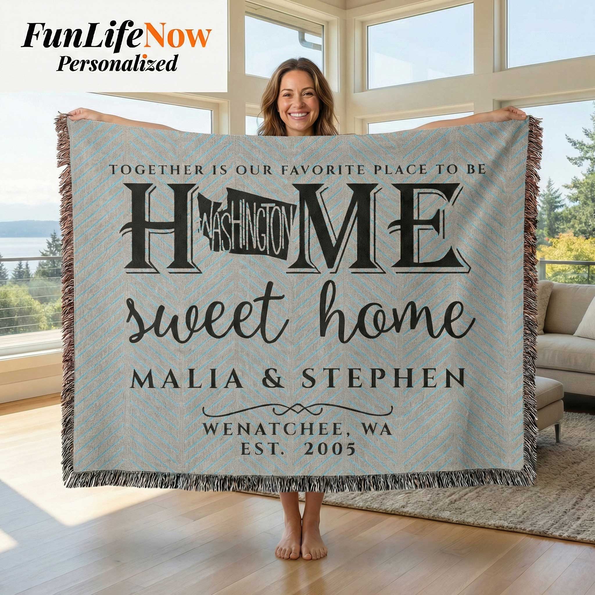 Person holding a personalized blanket with 'Home sweet home' text in a room with large windows.