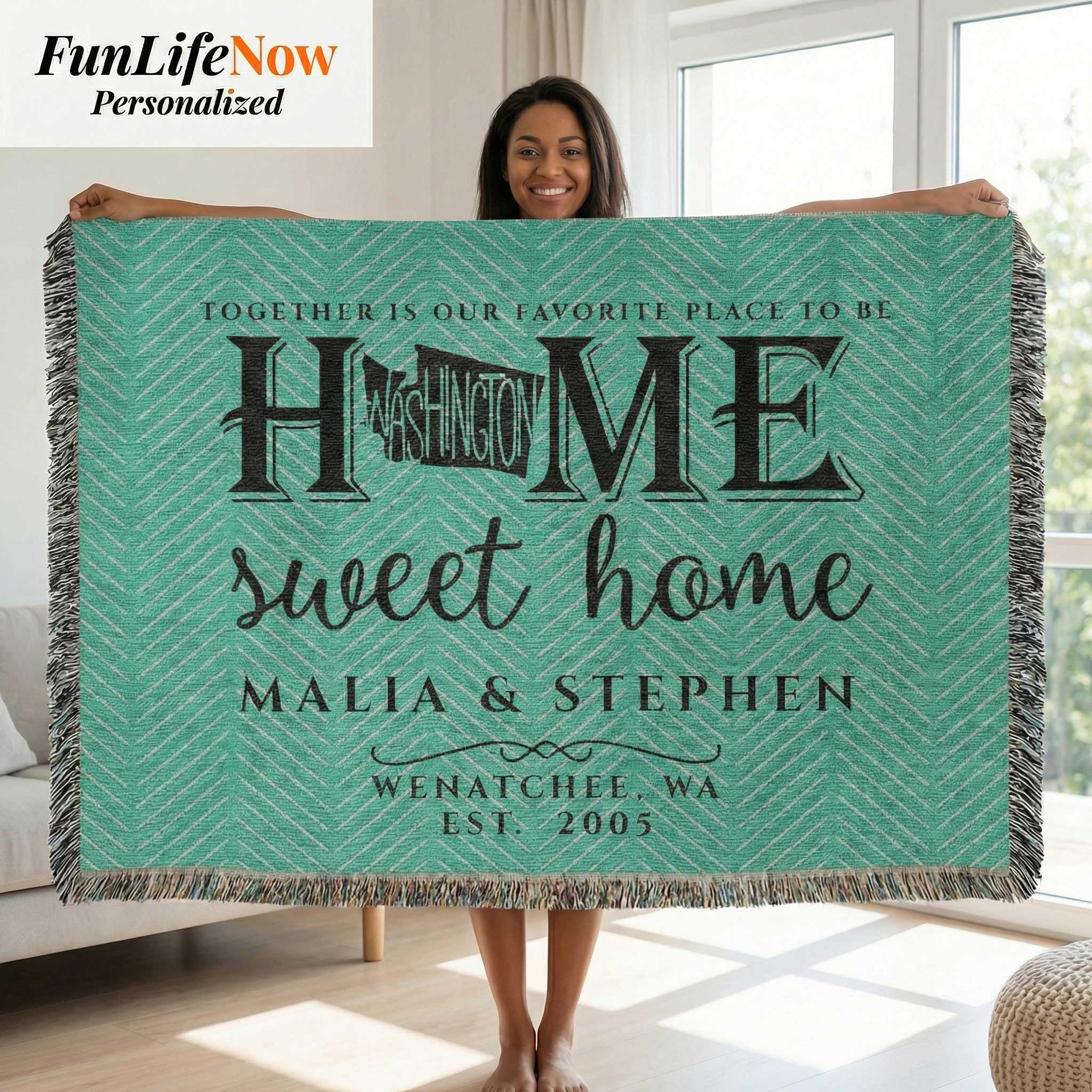 Person holding a personalized blanket with 'Home sweet home' text in a living room.