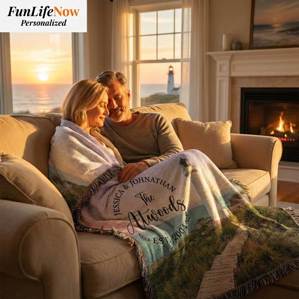 Couple sitting on a couch in a cozy living room with a personalized blanket, sunset through window, and fireplace. Blanket available at funlifenow.com